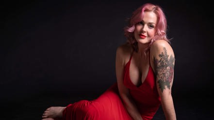 Storm Large poses in a red dress.