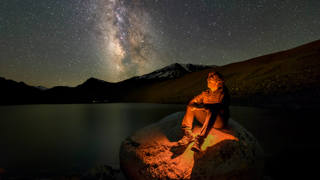 A man sits and gazes at the stars.