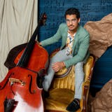 Marlon Martinez stands on a chair holding his cello.