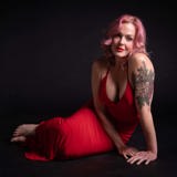 Storm Large poses in a red dress.