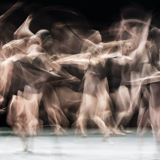 Long exposure photo of several dancers as they move across the stage.