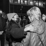 Photo of Esperanza Spalding embracing a patron outside the theater, with a mask on.