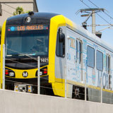 Photo of a yellow Metro train with blue sky above.