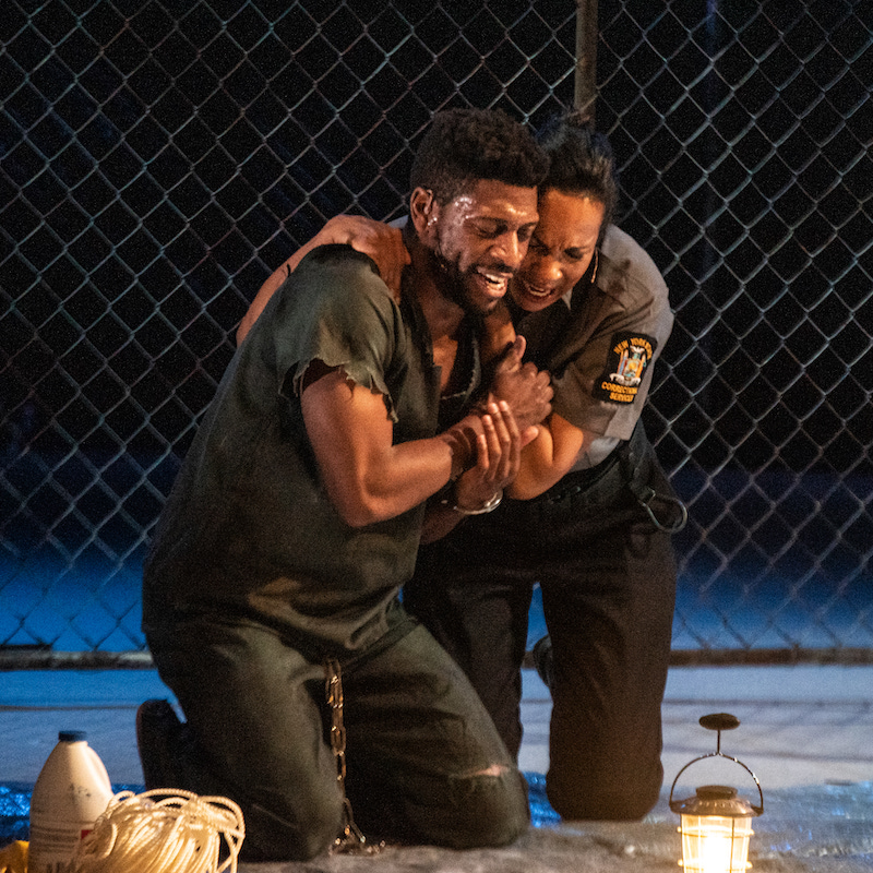Two performers' are huddled on their knees embracing one another in anguish.